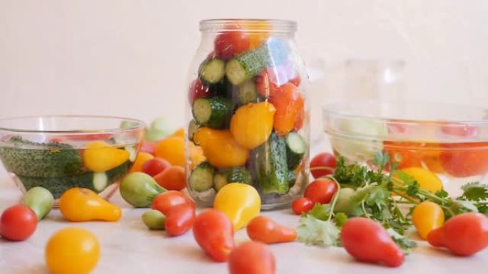 特写镜头将盐水倒入装有彩色西红柿和绿色黄瓜的罐子中，以便长期保存。罐装腌制的黄瓜和西红柿作为开胃菜
