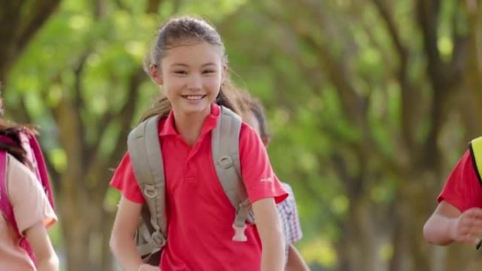 快乐的小学生在学校跑步。回到学校