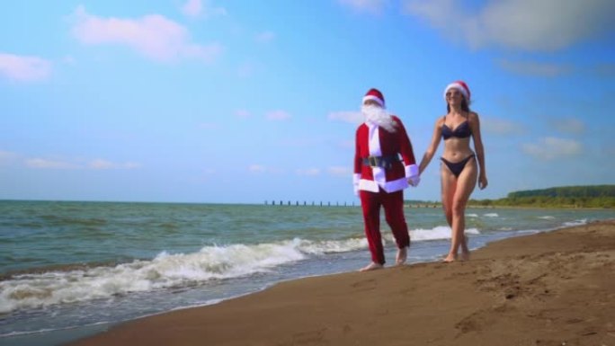 圣诞老人与性感的女人或女孩一起沿着海岸瘟疫行走