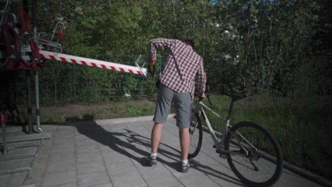 自行车基础设施。一名男子在德国慕尼黑使用双层自行车停车场。男性将自行车停在双层自行车停车场。欧洲的现