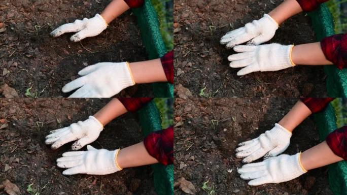 4k农民戴着白手套的手正在调整表土和堆肥。