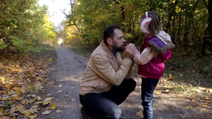 a man walks with a little girl in the autumn park,