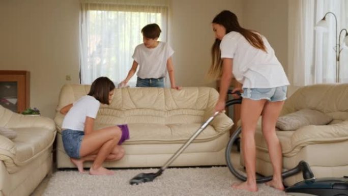 三个女孩三胞胎少年姐妹在家用吸尘器打扫房间用抹布擦灰尘