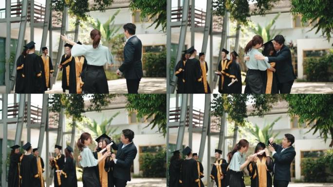 自豪的亚洲华裔父母带着女儿在大学大楼外的大学毕业礼服