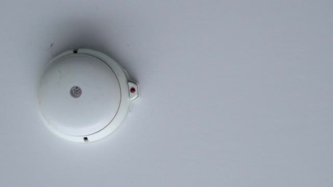 白色烟雾报警器的特写。向上看。背景是塑料天花板。