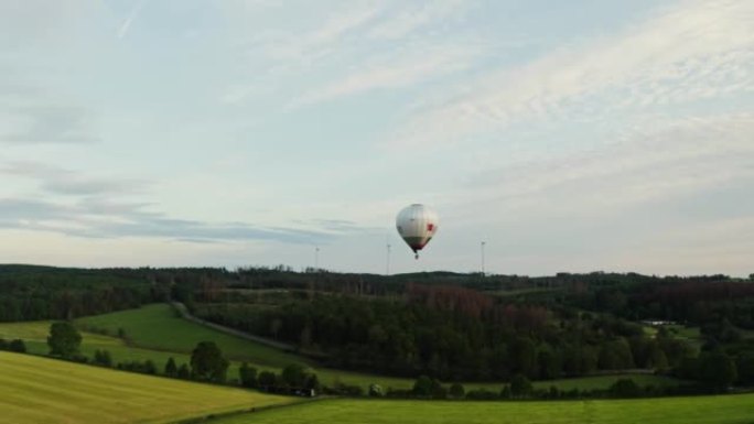 天空中的热气球在阳光明媚的日子里飞过绿色的田野，德国。