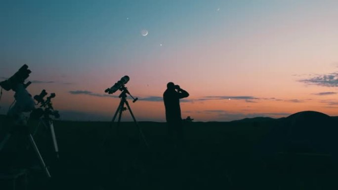 用天文望远镜，天文摄影机和双筒望远镜观察夜空的人。