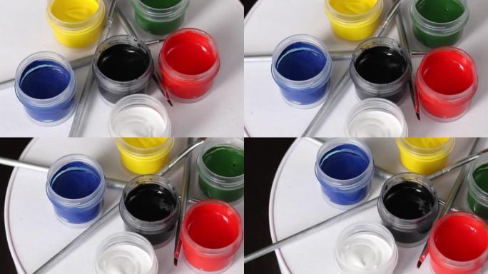 一套水粉和刷子。打开油漆罐。在主题表上旋转。特写。