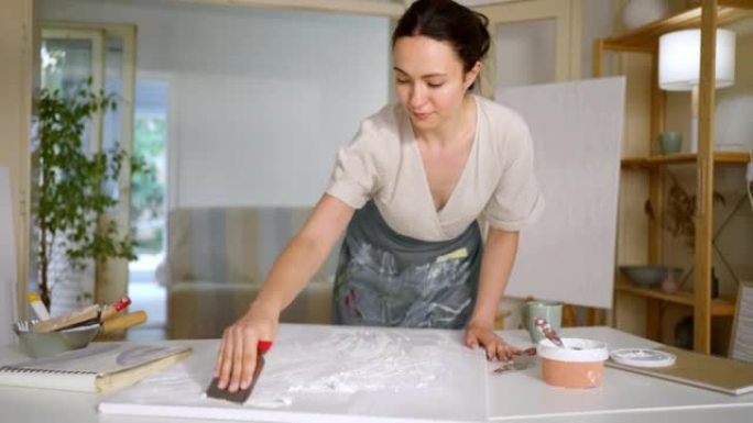 高加索女艺术家用尖刻的腻子和抹子在画布上创作艺术