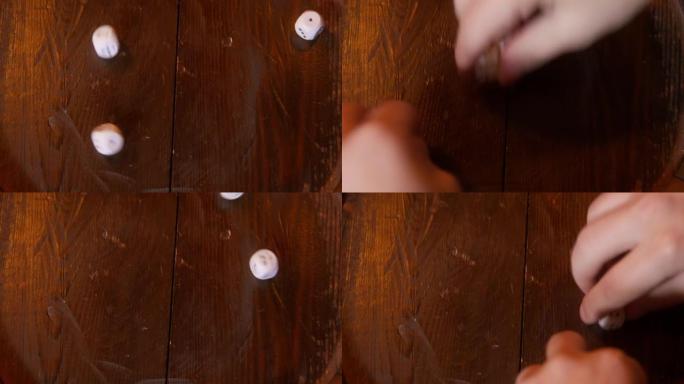 手将骰子扔在木制表面上。手掌与立方体