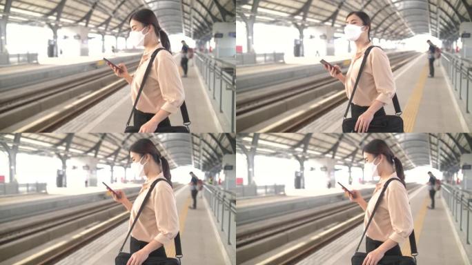 妇女在曼谷的车站使用智能手机和等候火车