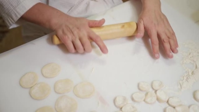 女性的手用rolling面杖卷起饺子的坯料，用rolling面杖卷起面团，