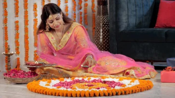 一位穿着传统服装的迷人女士用Diyas装饰地板上的Rangoli