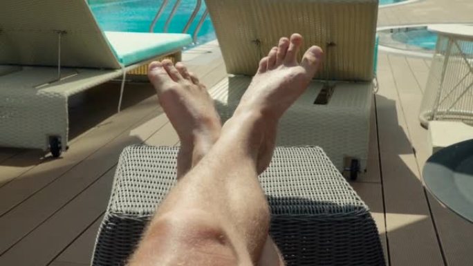 一个男人晒日光浴，看着晒黑的腿的观点。