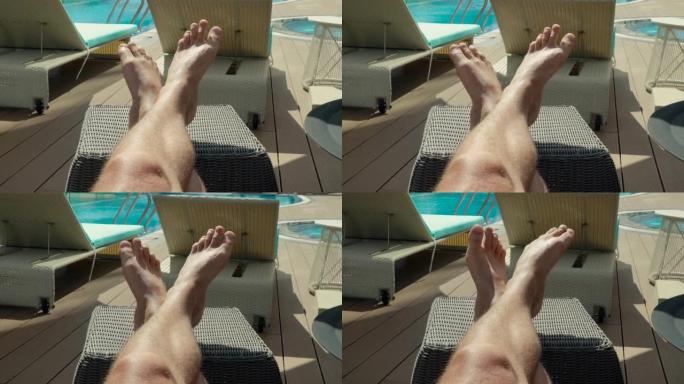一个男人晒日光浴，看着晒黑的腿的观点。