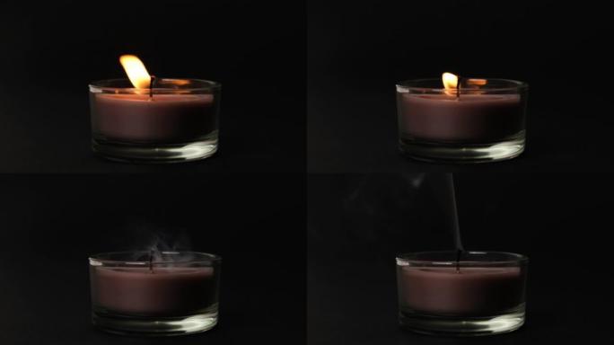 圆棕色单蜡烛在黑暗中摇曳。侧视图。蜡烛在玻璃烛台燃烧在黑暗的背景。慢动作全高清视频。吹灭蜡烛。