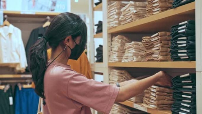 Asian young woman is walking to pants shelf and pi