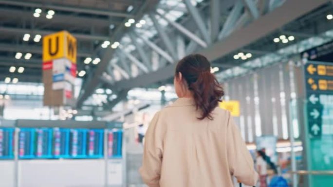 女人在机场航站楼带着行李箱行走，旅游旅行概念