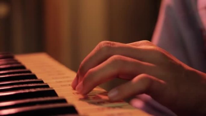 亚洲女孩在家里的夜晚通过沙发上的移动应用学习弹奏键盘乐器，生活方式理念。身体部位。