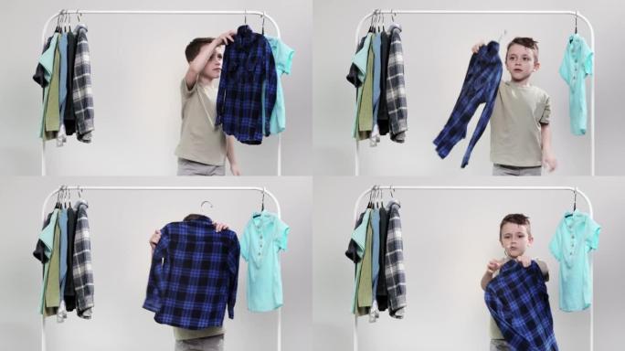 男孩学龄前儿童站在衣架旁边，收拾衣服，为今天选择衣服。