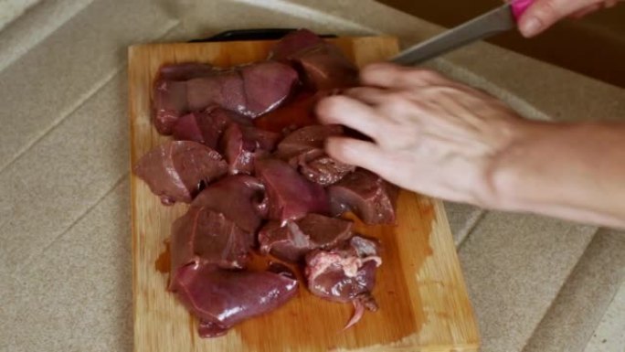 在厨房板上用刀切猪肝的特写镜头。