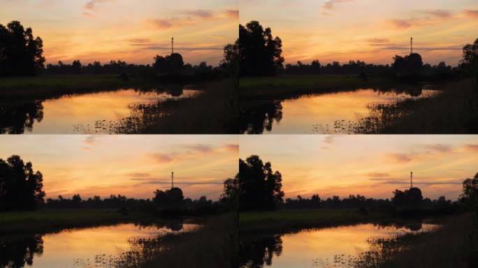 太阳在稻田里慢慢升起。泰国日出，感觉非常温暖。希望符号。四周轮廓优美。