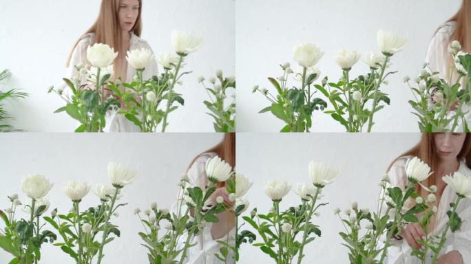 一个长发的花店女孩摆出美丽精致的白菊。摄像机从左到右移动。
