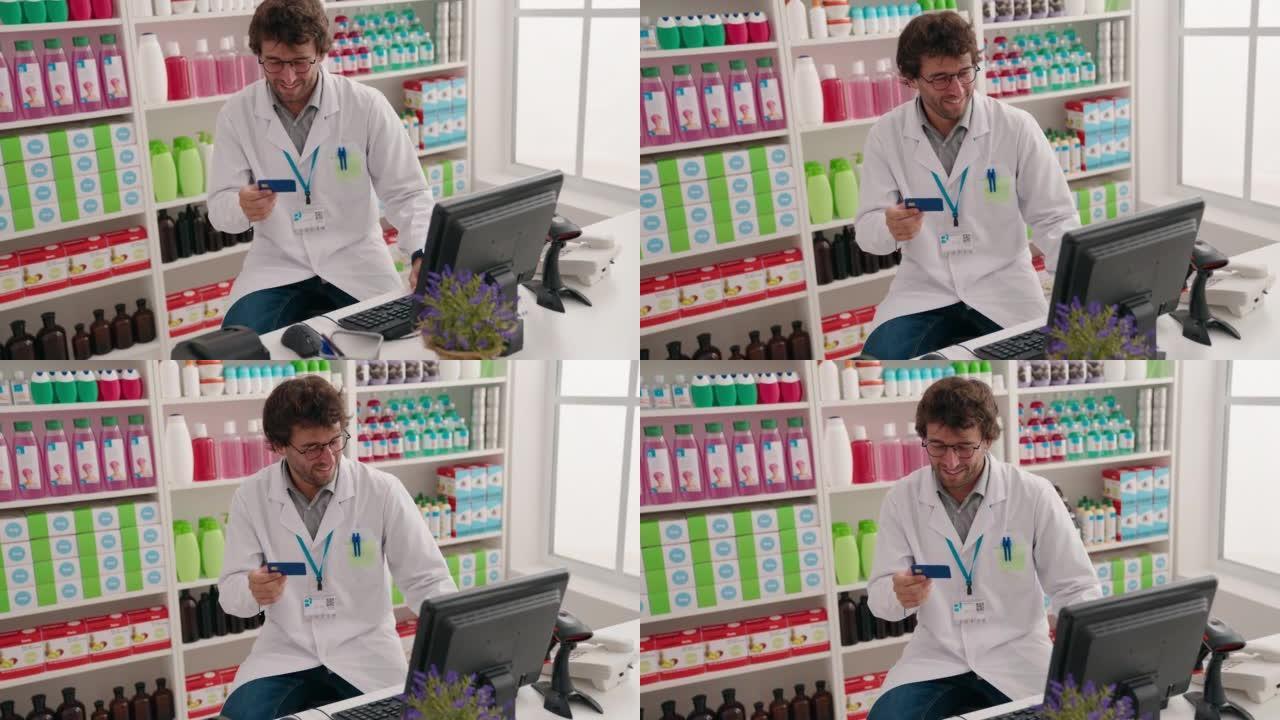 年轻的西班牙裔男子药剂师在药房使用持有信用卡的计算机