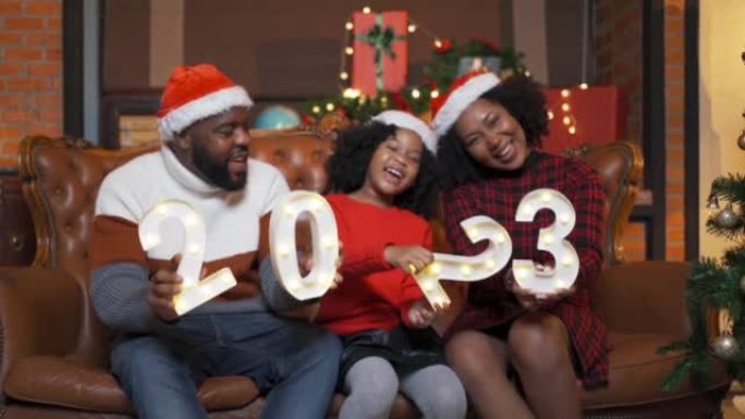 一个非裔美国黑人家庭，女人，父亲，母亲和2023新年的小女孩，在圣诞节前夕圣诞节快乐的聚会上赠送礼物