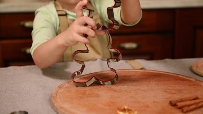 选择性地关注站在家庭厨房餐桌旁的一个漂亮小女孩手中的姜饼切刀