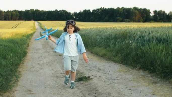 快乐的男孩在晴天扔纸飞机在田野里奔跑。儿童游戏，幻想和梦想。