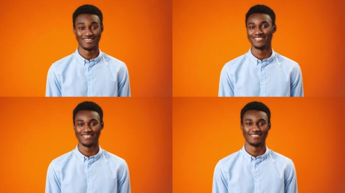 积极的非洲年轻人微笑着在橙色背景下点头