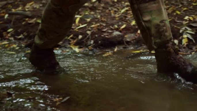 一个士兵沿着河边的脚步。倒影在水里。湿的贝雷帽。