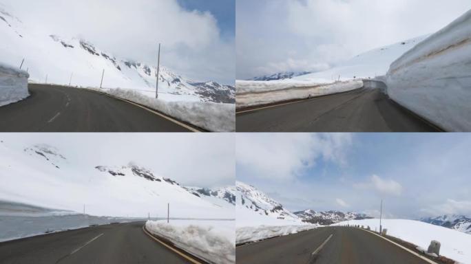 令人眼花Time乱的延时行驶在高阿尔卑斯山的一条潮湿的柏油路上，道路旁的路堤上积雪残存，POV。