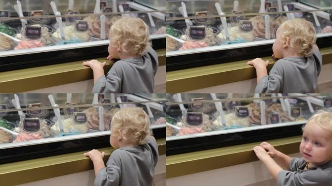 可爱的金发小孩渴望从家庭咖啡馆展示中选择冰淇淋，各种口味。孩子喜欢吃甜食，但不顾后果地吃糖对孩子的牙