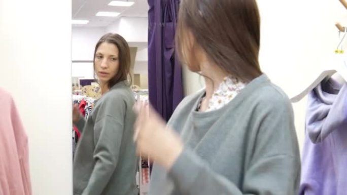 一名年轻女子在试衣间的镜子前试穿套头衫