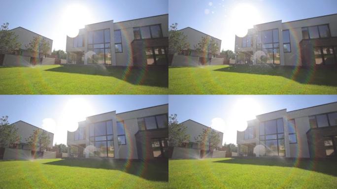 绿草自动浇水。私人住宅的自动草拼接智能住宅的概念。水滴落在相机镜头上。太阳的光线将背光照射到镜头中。