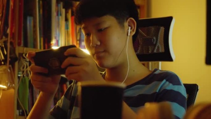 亚洲少年男孩在晚上在家玩手机游戏，生活方式概念。