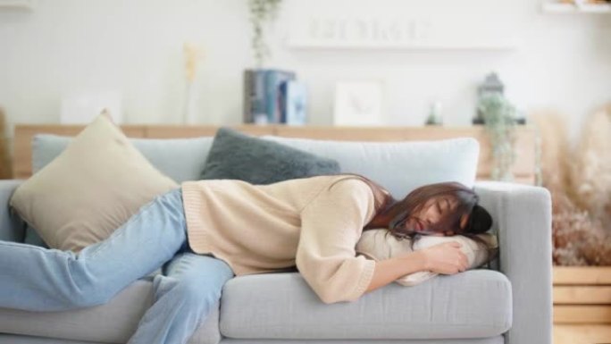 亚洲妇女在家躺在沙发上休息，下班后感到筋疲力尽，精力不足，或劳累过度，太累，缺乏动力