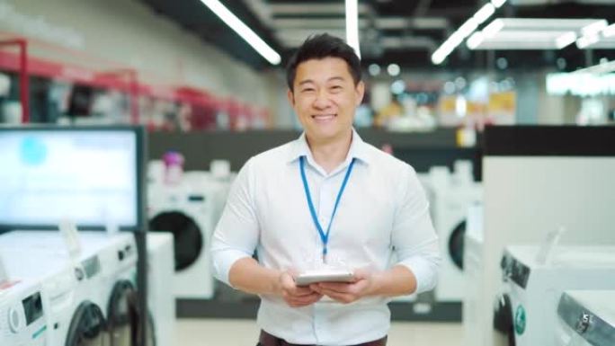 肖像微笑男亚洲销售顾问专家站在家电卖场看相机