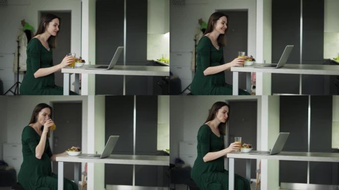 Pregnant woman sitting and eats salad while having