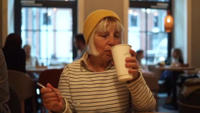 快乐的50年代女人在咖啡馆喝茶和蛋糕