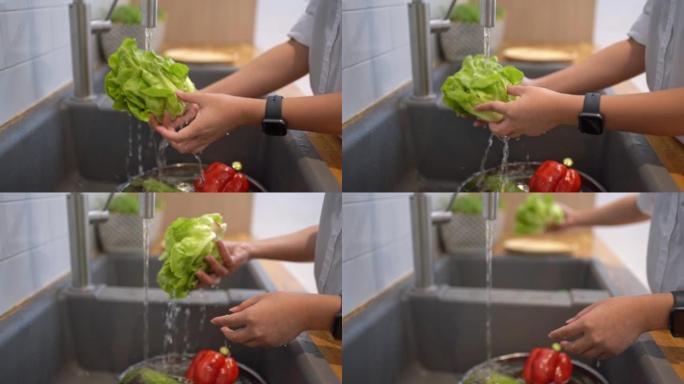 一位亚洲妇女的手在厨房里洗绿色蔬菜。健康的生活方式