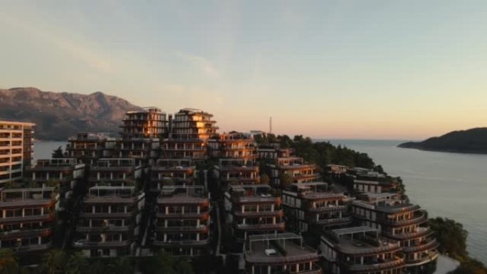 山腰精英住宅区和豪华酒店的全景，位于一个令人难以置信的美丽海湾，被炽热的日落金色光线照亮，无人机射击
