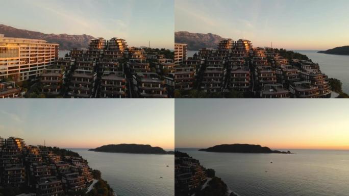 山腰精英住宅区和豪华酒店的全景，位于一个令人难以置信的美丽海湾，被炽热的日落金色光线照亮，无人机射击