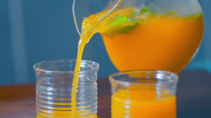 橙汁倒入玻璃杯中。柑橘汁飞溅慢动作镜头。家庭早餐，健康饮料生活方式，维生素。浇注概念