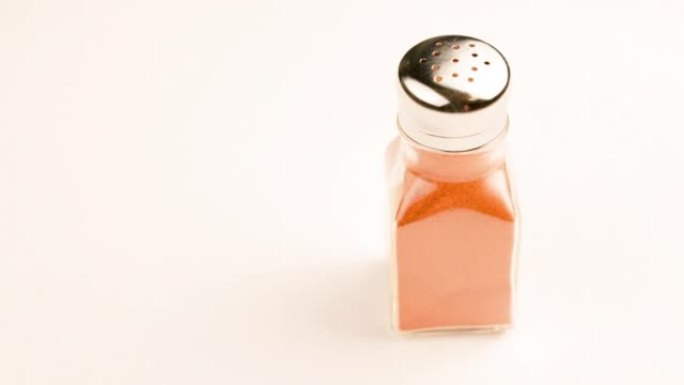 玻璃胡椒罐，不锈钢盖满红色辣椒粉，白色背景纺丝