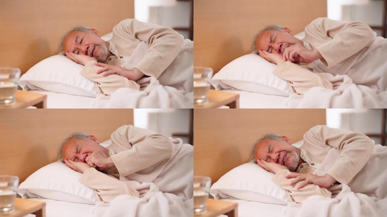 亚洲老年男性躺在床上，退休后呆在家里。不幸的老年残疾人咳嗽，担心医疗保健问题。医院医疗保健和医疗概念