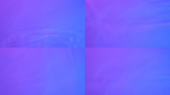 霓虹蓝色，粉红色和紫色的水渐变纹理，带有水滴，飞溅和波浪。蓝色和粉红色渐变的有机水色，折射光慢动作视