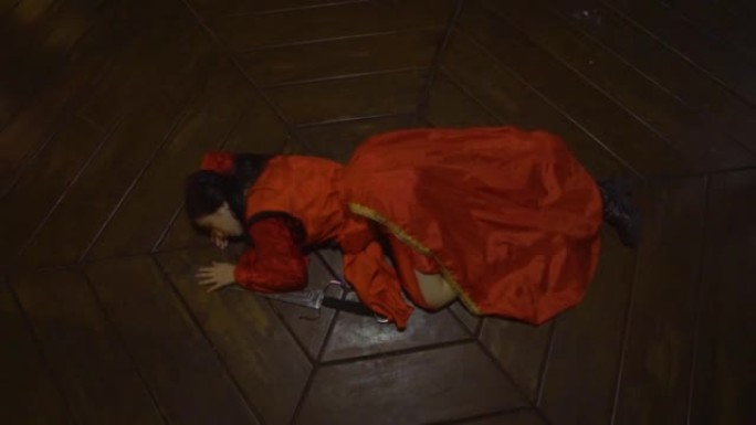 一名中国妇女穿着红色的中国连衣裙睡在剑旁的木地板上